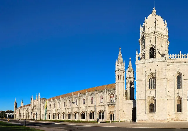 L'ala occidentale del monastero con le sue sottili torri a pinnacoli e il campanile a cupola della chiesa, in pietra chiara sotto un cielo azzurro intenso