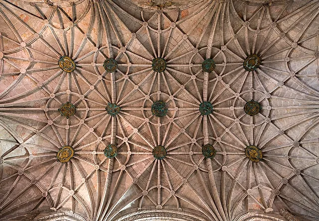 Mirando directamente hacia arriba, la bóveda de nervaduras en forma de estrella de la iglesia, con claves redondas decoradas donde se unen las nervaduras